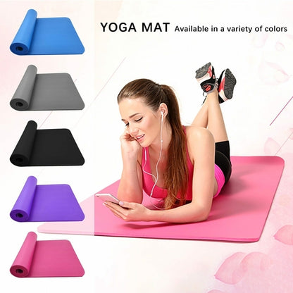 Woman using a smartphone on a pink yoga mat with yoga mats in various colors displayed.